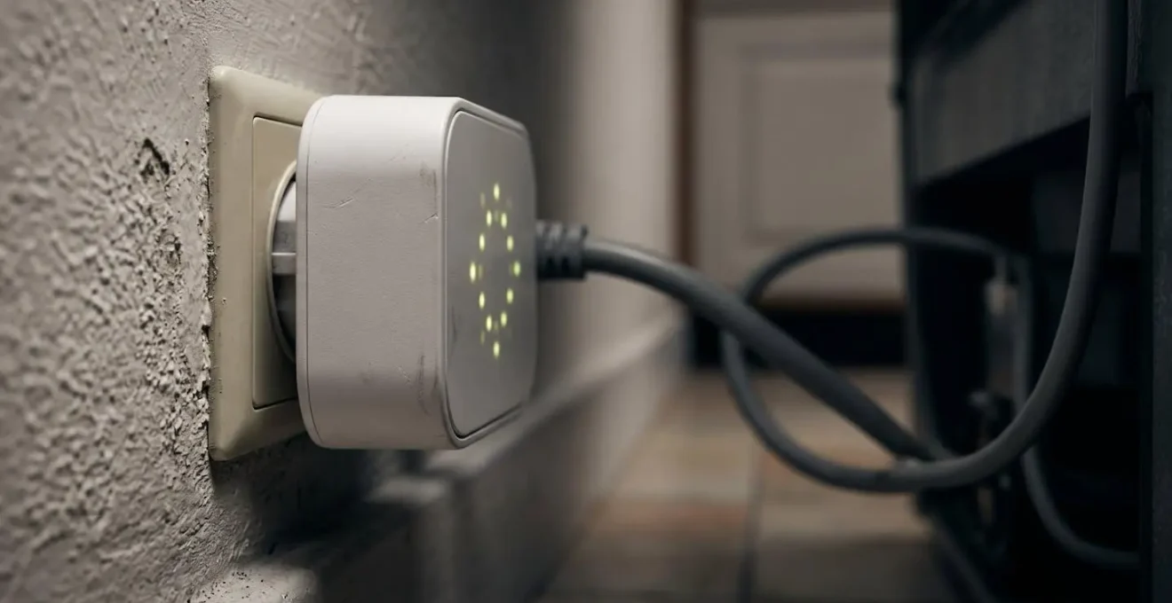 Gros plan sur une prise connectée branchée derrière un réfrigérateur avec affichage lumineux