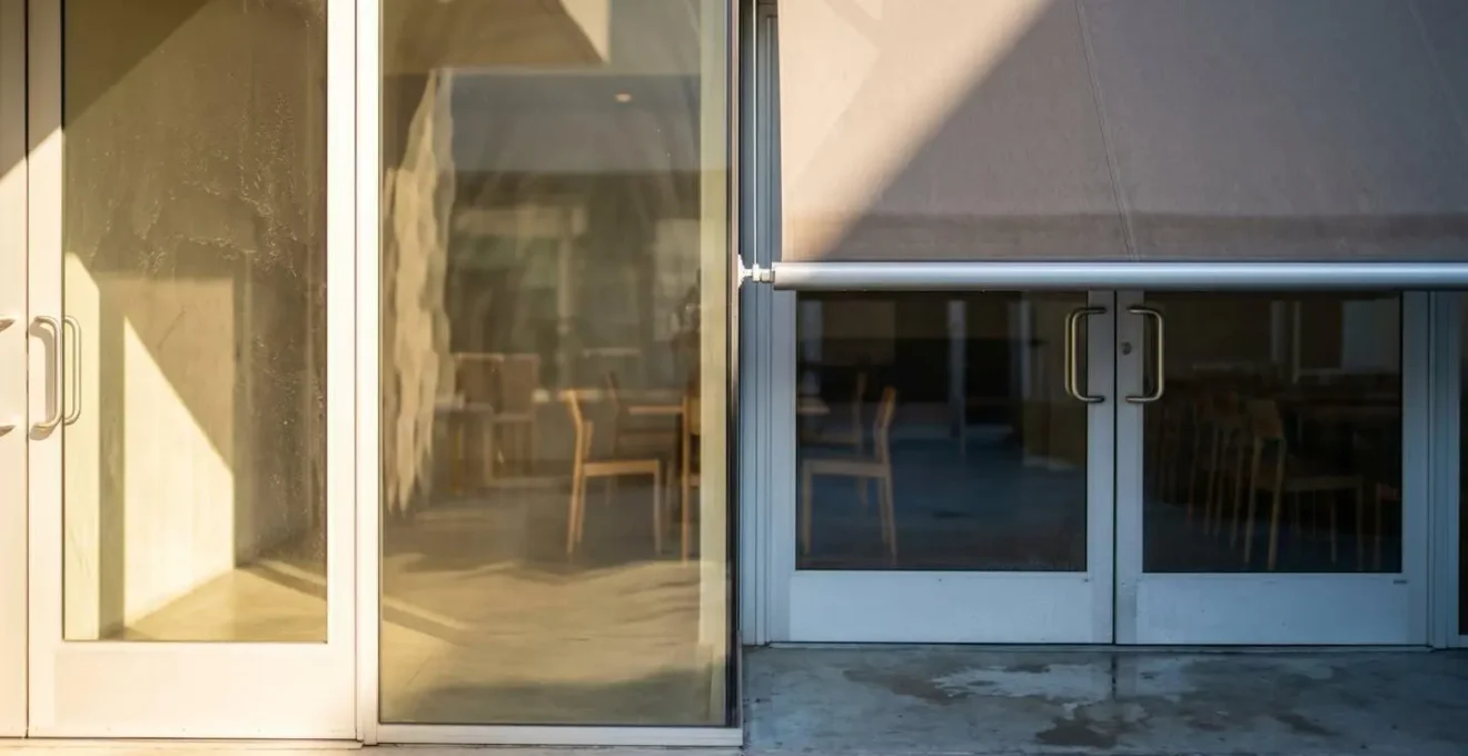 Store banne déployé automatiquement protégeant une baie vitrée du soleil et maintenant la fraîcheur à l'intérieur de la maison.