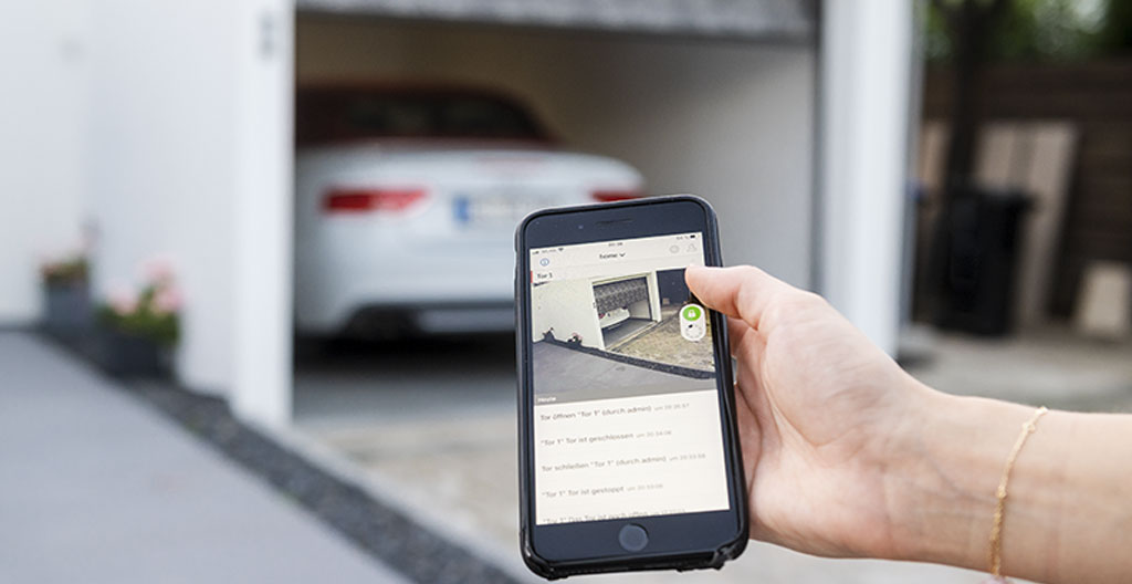 Écran de smartphone affichant une interface d'application domotique avec statut porte de garage indiquant fermée et verrouillée, badge de notification visible